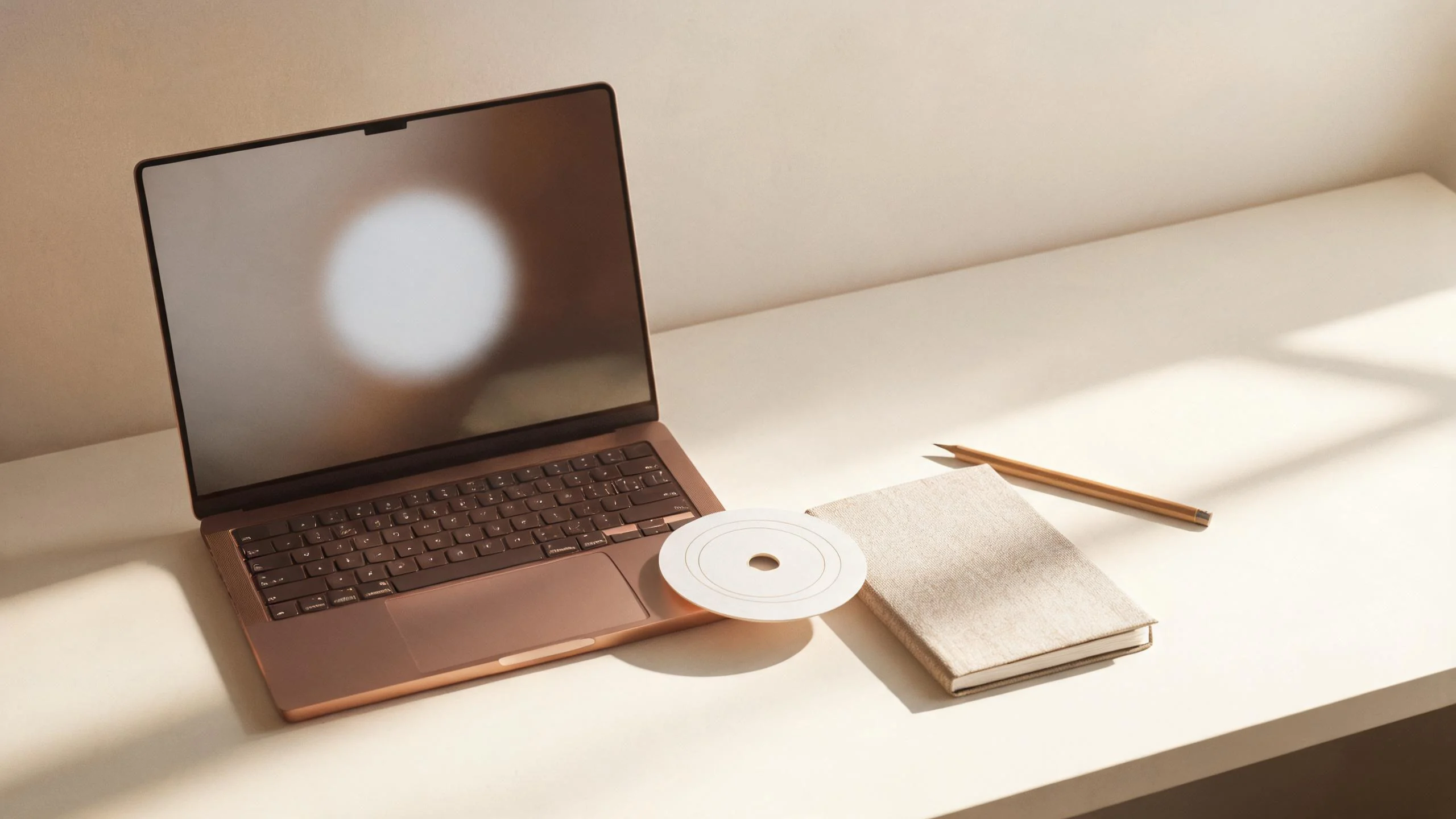Laptop with an abstract circular interface beside a printed chart and linen notebook
