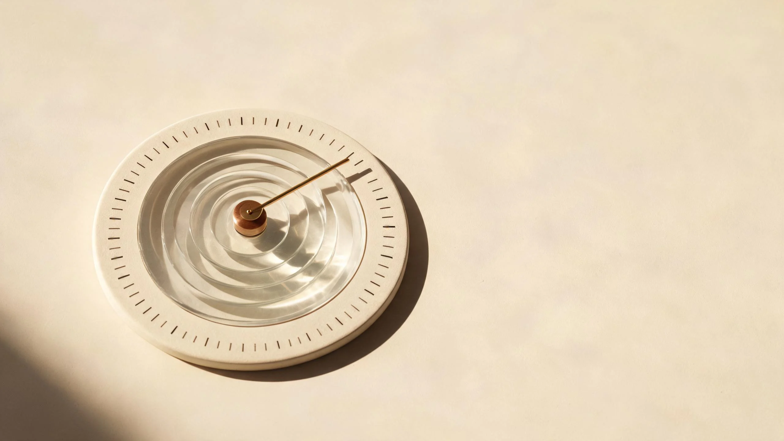 Translucent glass age wheel with fine perimeter ticks and a copper timing pointer